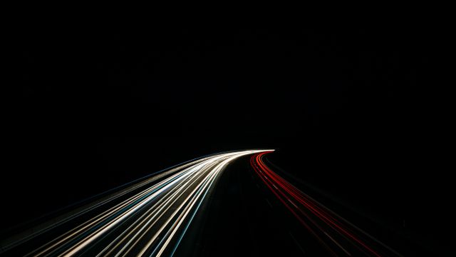 Lichtstreifen von Fahrzeugen auf einer Autobahn bei Nacht als Symbol für Geschwindigkeit
