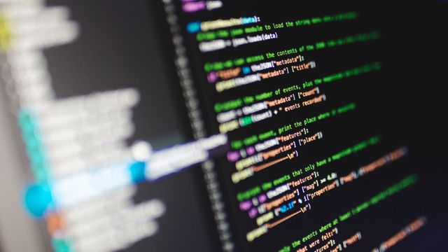 Nahaufnahme von farbigem Quellcode auf einem dunklen Monitor